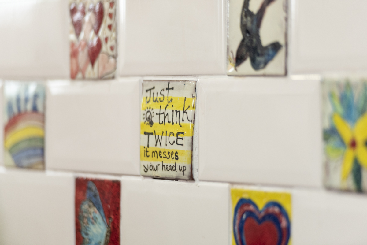 Hand painted tiles at the MASH drop-in. One reads Just Think Twice. Others have birds, flowers and colourful hearts