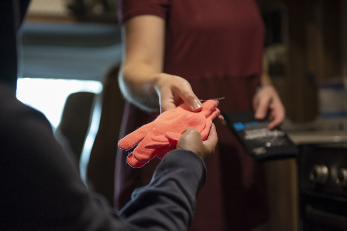 A hand passing over a pink pair of winter gloves